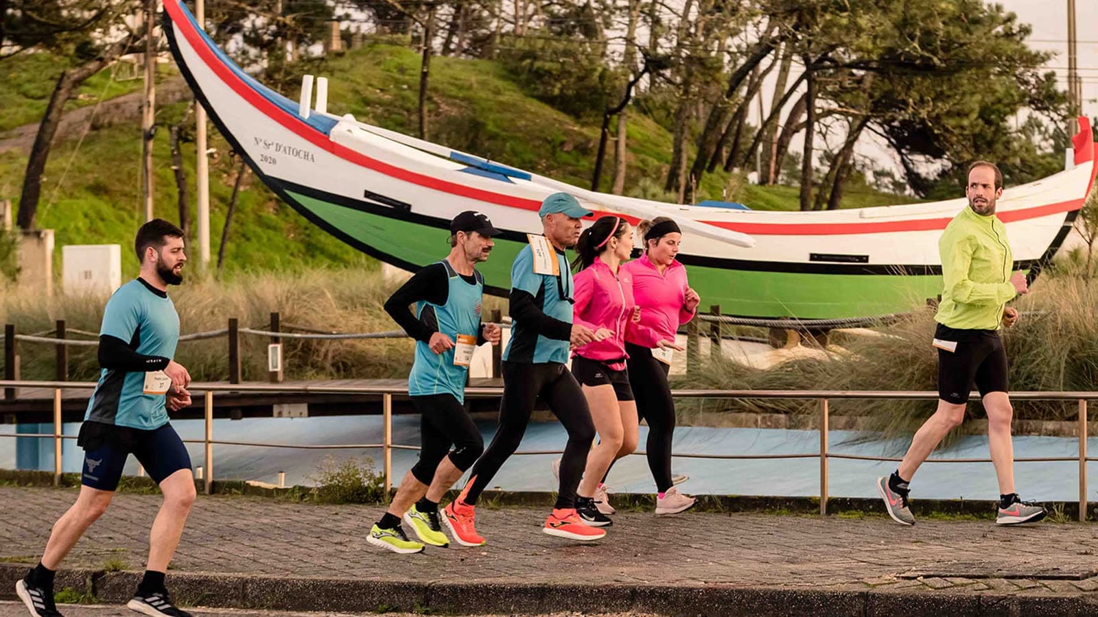 Corredores a passar junto a um barco da arte-xávega