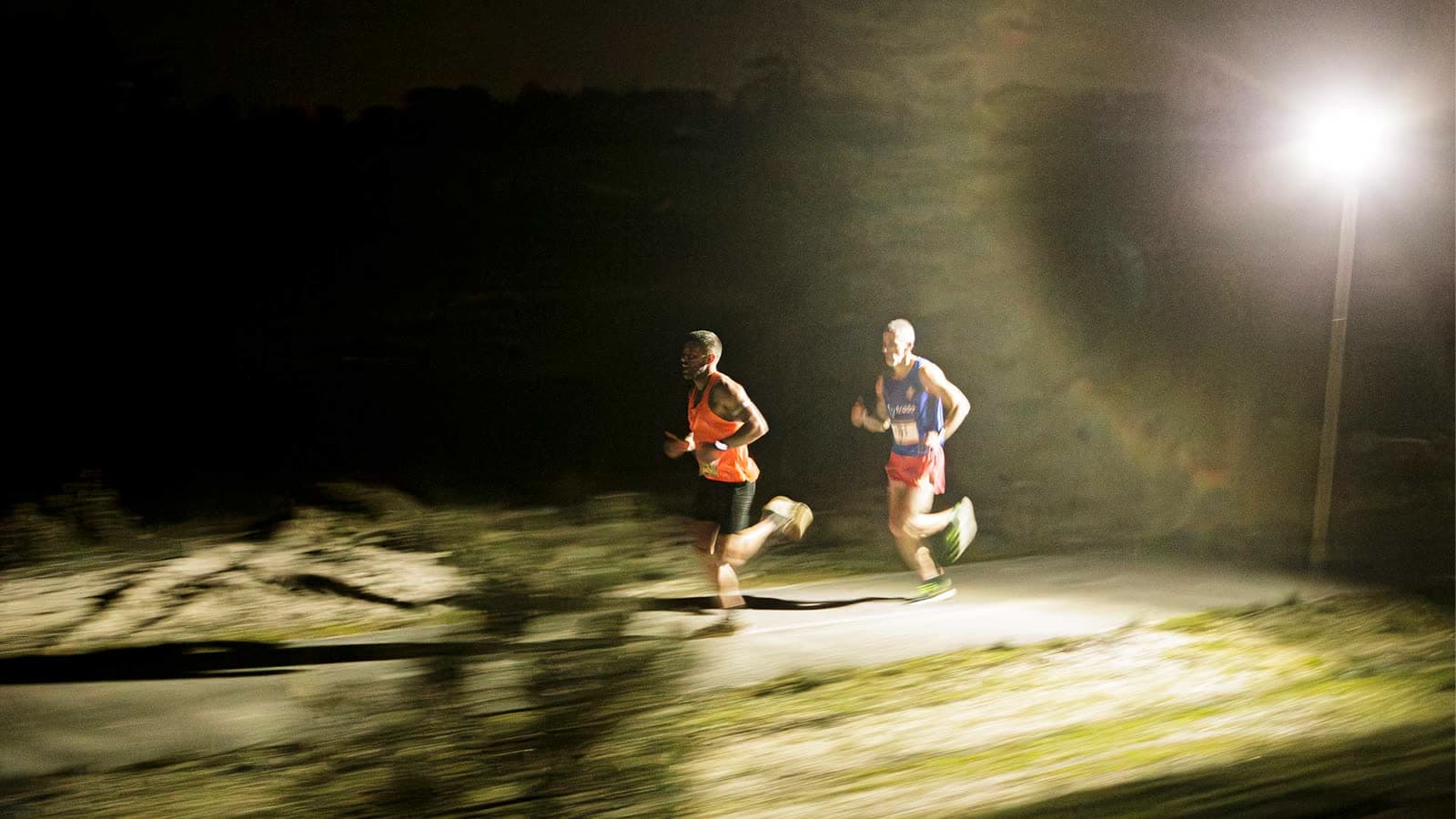 Dois atletas a correr à noite junto às dunas